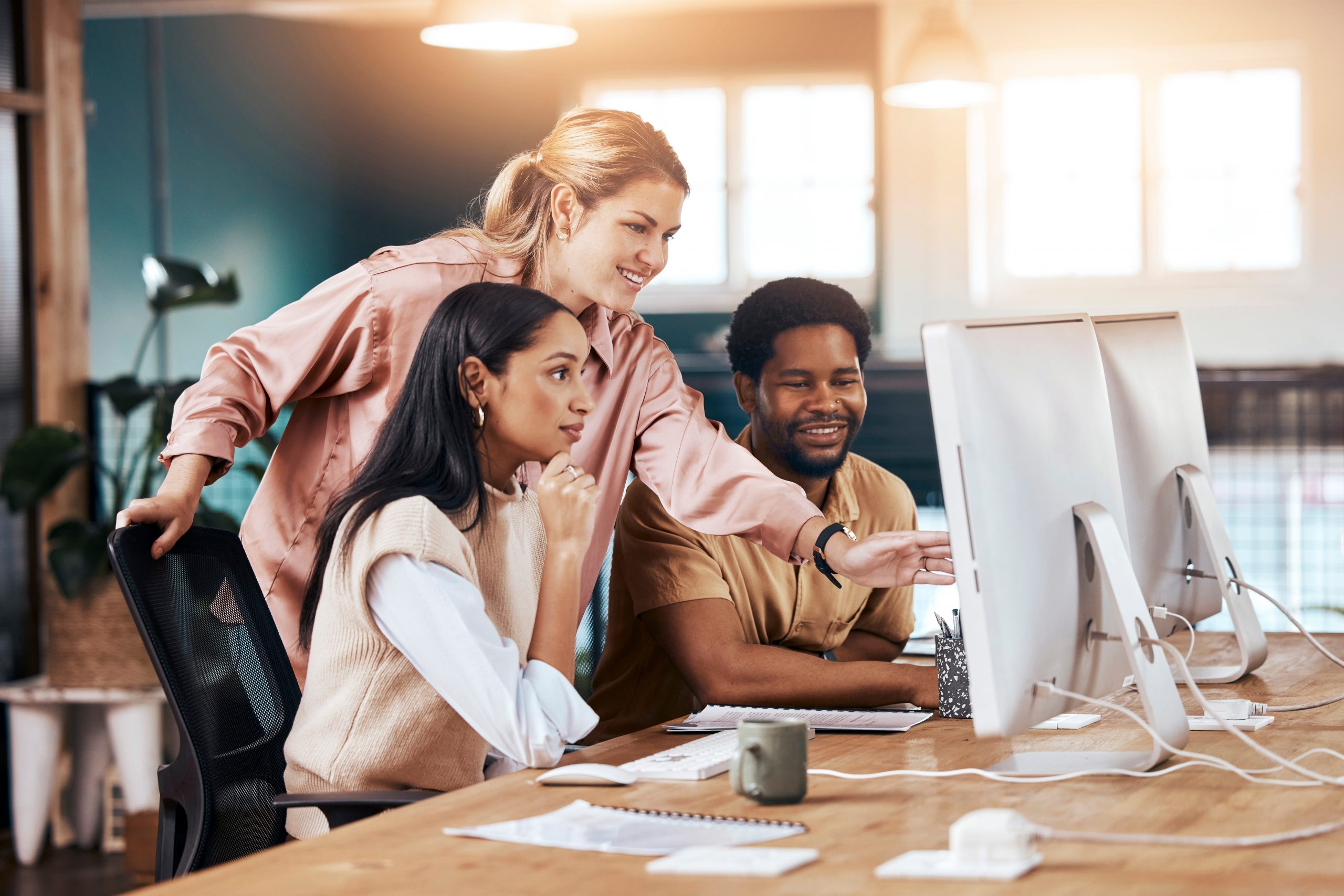 Business team, computer and happy mentor talking to people at office desk for motivation. Entrepreneur women and man at pc for discussion about coaching, management and online planning or training